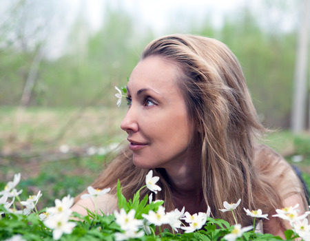 The young beautiful woman on a glade of blossoming snowdrops in the early spring, toningの写真素材