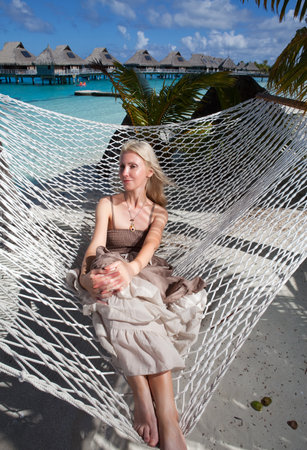 the beautiful woman in a long sundress in a hammock on a sea backgroundのeditorial素材