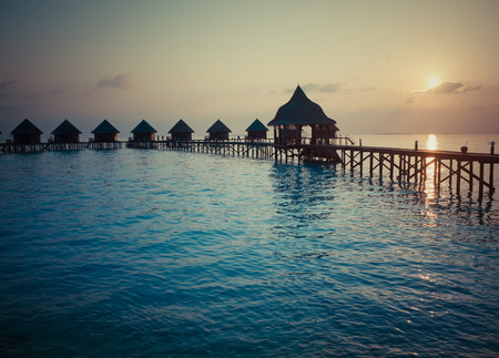 Silhouette of lodges in the sea at sunset. Maldives,with a retro effectの写真素材