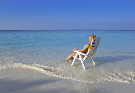 Young pretty woman in a beach chair in seaの写真素材