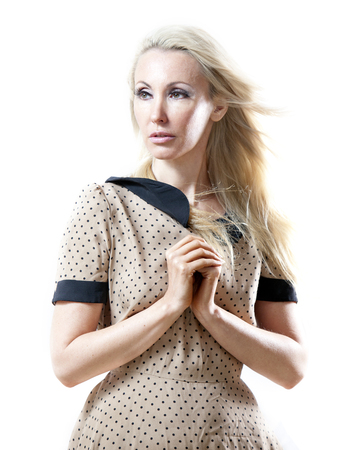 The beautiful thoughtful woman in a beige retro style dress with the fair long hair fluttering downwind.の写真素材