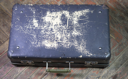 Old shabby suitcase on latches on a wooden floorの写真素材