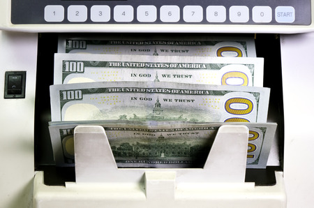 electronic money counter machine is counting is counting the American hundred-dollar (US dollars) banknotesの写真素材