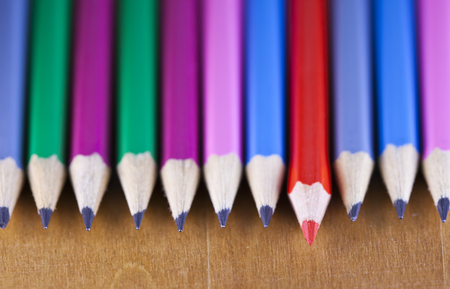 black lead pencils lie in a row, one pencil has a red core and put forward , small depth of sharpnessの写真素材