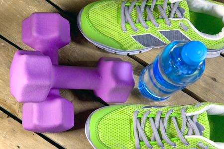 Sports sneakers, dumbbells, drinking water on a wooden backgroundの写真素材
