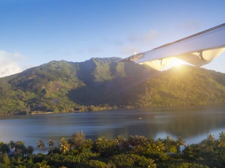 Aerial view from a flying airplane on the tropical island at sunset