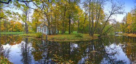 old blue ruined house by the river in autumn park with bright foliageの写真素材