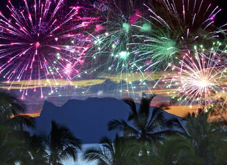 Festive New Year's fireworks over the sea and mountains on tropical islandの写真素材