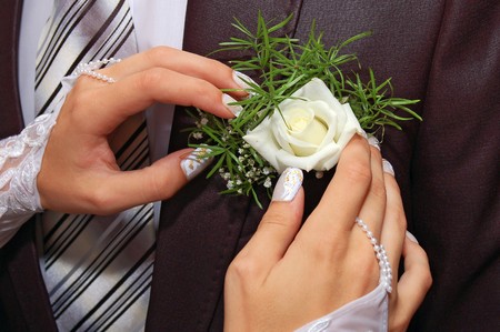 a hands fiancee on the buttonhole of groom
