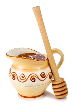 honey in a jug and wooden stick isolated on white backgroundの写真素材