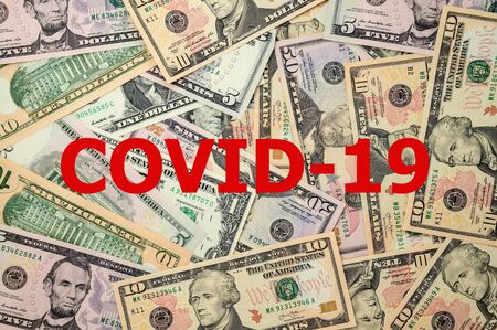 Scattered US dollars over which is the COVID-19 inscription.