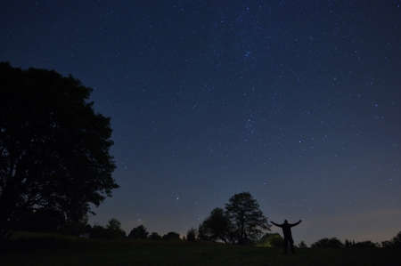 A man with a headlamp looks at the starry sky.の写真素材