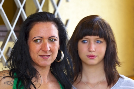 Portrait of a mother and daughter in background a window with a grid, outdoor  in a small city Dillingen,  Saarland   Germanyの写真素材