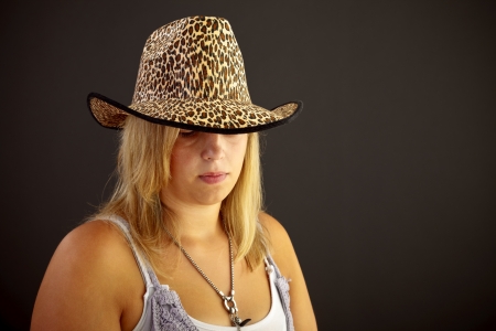 Young blond woman with hat on black backgroundの写真素材