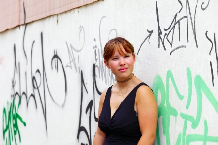 Portrait of a young woman in the background a white  wall with graffiti,  in small city Saarlouis, Saarland / Germanyの写真素材