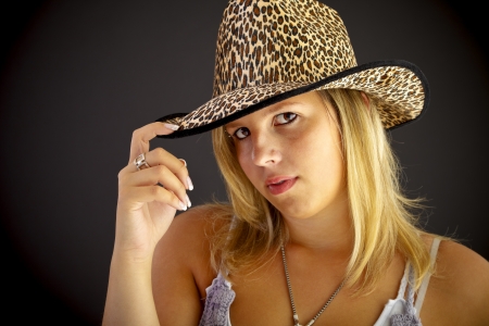 Young blond woman with hat on black background, studio shot.の写真素材