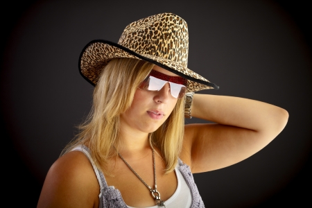Young blond woman with hat on black background, studio shot.の写真素材