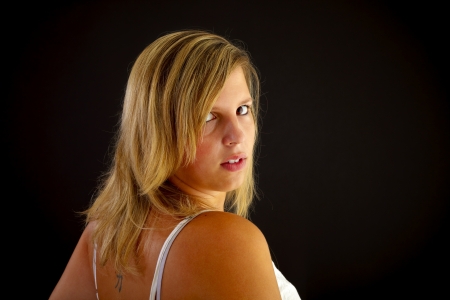 Young blond woman on black background, studio shot.の写真素材