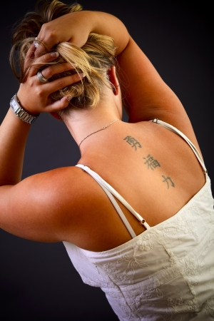 Young blond woman, back side on black background, studio shot.の写真素材