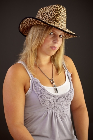 Young blond woman with hat on black backgroundの写真素材