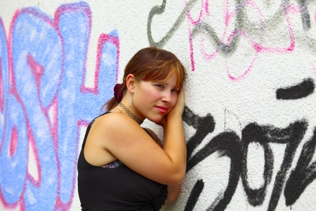 Portrait of a young woman in background a white wall with graffiti, outdoor in a small city Saarlouis / Saarland / Germanyの写真素材