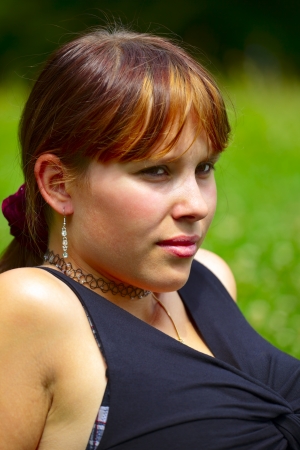 Portrait of a young woman sits on a green meadow in the sun, outdoor in a small city Saarlouis. Saarland / Germanyの写真素材