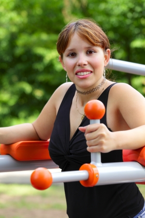 A young woman sitting on sport device and laughs in the pause between sport exercises. Outdoor in park in city Saarlouis, Saarland / Germany.の写真素材