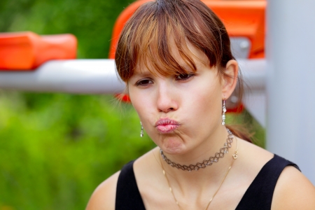 A young woman sitting on sport device and laughs in the pause between sport exercises. Outdoor in park in city Saarlouis, Saarland / Germany.の写真素材