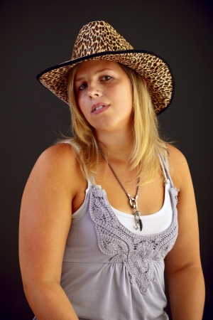 Young blond woman with hat on black background, studio shot.
の写真素材
