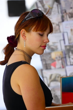 A young woman looks at the book, on a street in small city Saarlouis, Saarland / Germanyの写真素材