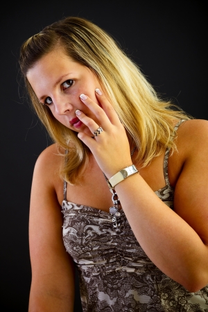Young blond woman on black background, studio shot. の写真素材