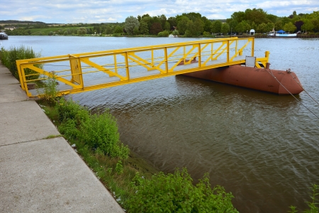 View of a small pier on river Moselle(border river) in city Remich / Luxembourg, evening, summer, in the distance(to right) a campground in Germanyの写真素材