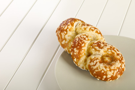 Bun with cheese gratin on plate,  white wooden background.の写真素材