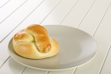 Bread roll on ceramic plate, white wooden background.の写真素材
