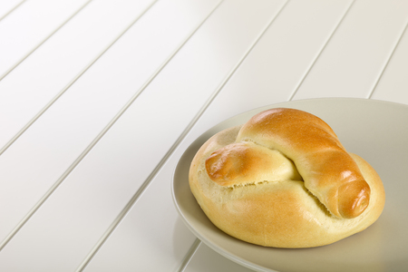 Bread roll on ceramic plate, white wooden background.の写真素材