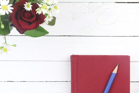 red roses, blue pencil and red diary on white wooden background with copy space.の写真素材