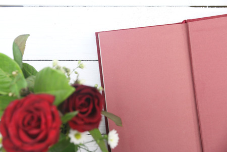 red roses and red diary on white wooden background with copy space.