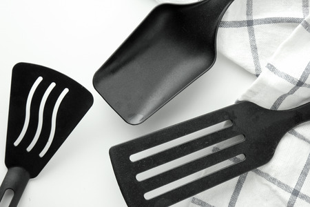 black ladle and spade of frying pan on the white tableの写真素材