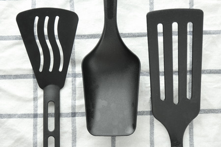 black ladle and spade of frying pan on the white tableの写真素材