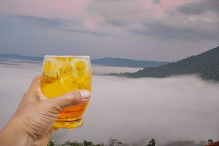 A hand is holding a glass of cold beer.の写真素材