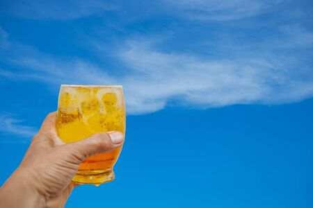 A hand is holding a glass of cold beer.の写真素材