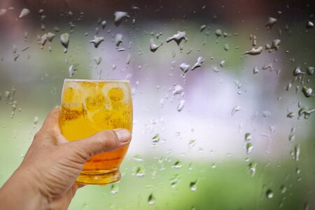 A hand is holding a glass of cold beer.の写真素材