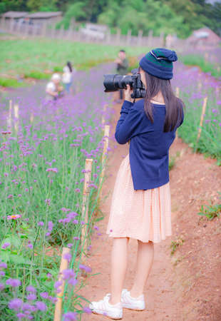 Young female tourists taking pictures in flower garden