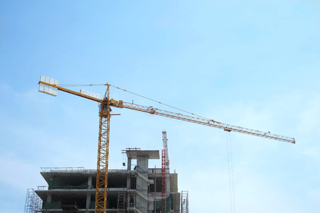 Yellow crane and building under construction on blue skyの写真素材