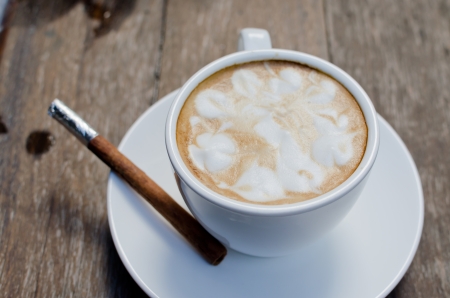 A cup of hot latte with cinnamon on wood backgroundの写真素材