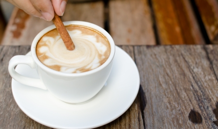 A cup of hot latte with cinnamon on wood backgroundの写真素材