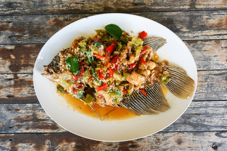 Fried Giant gourami fish with sweet and sour sauce on wood tableの写真素材