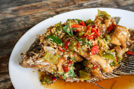 Fried Giant gourami fish with sweet and sour sauce on wood tableの写真素材