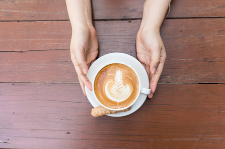 A cup of hot latte coffee and meringue on wood tableの写真素材