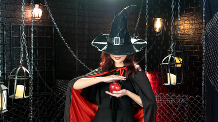 Magic on Halloween. Beautiful woman dressed as witch for Halloween using magical with apple in halloween themeの写真素材